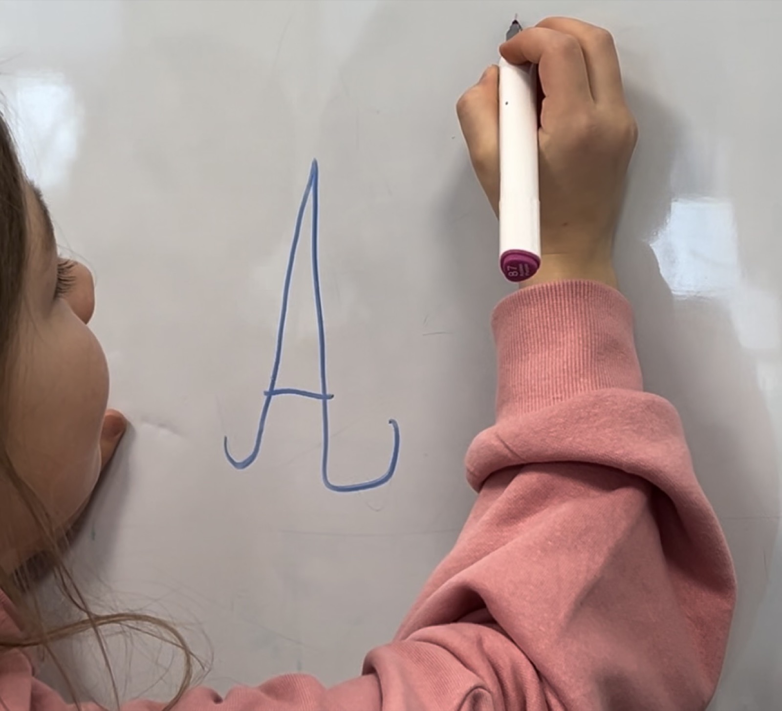 A girl writes the letter A on a board