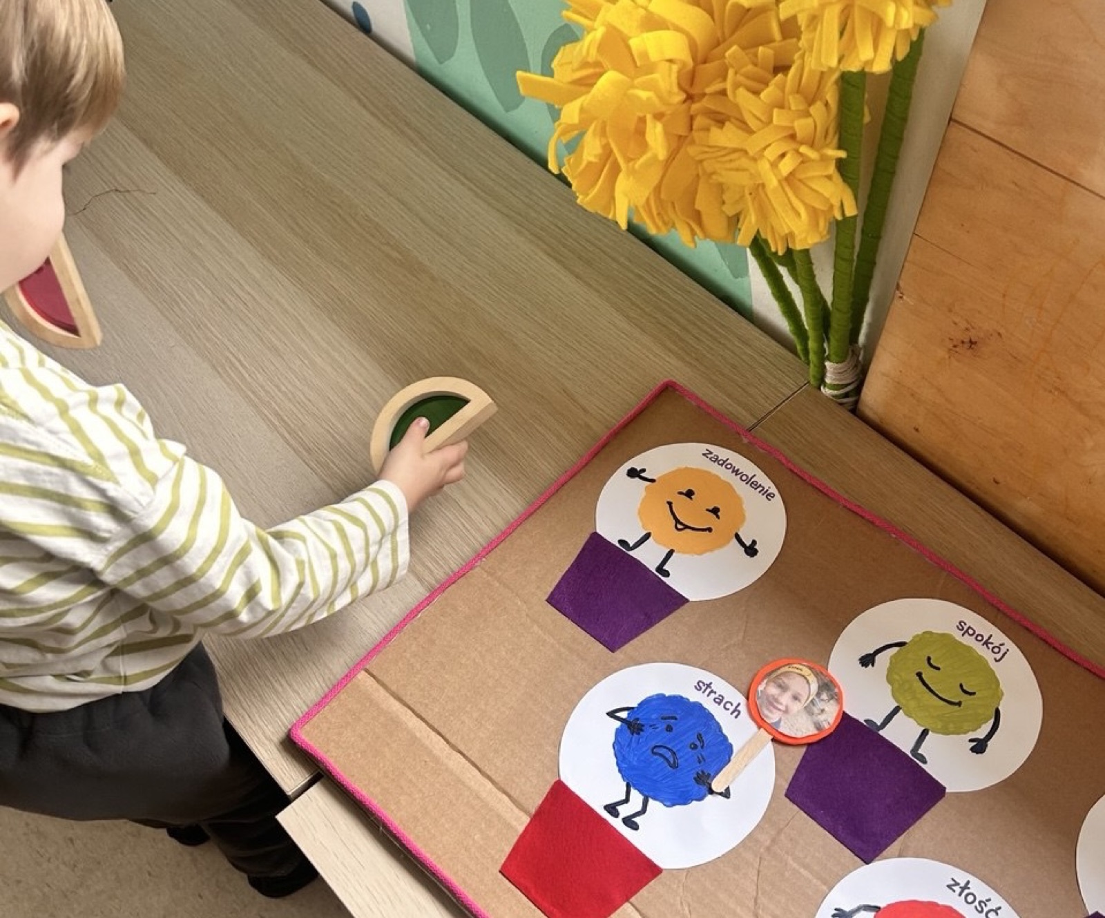 A boy arranges emotion cards on a sensory board